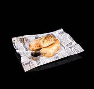 Fotografía de producto de wrap relleno servido con salsa. Wrap relleno con verduras y salsa
